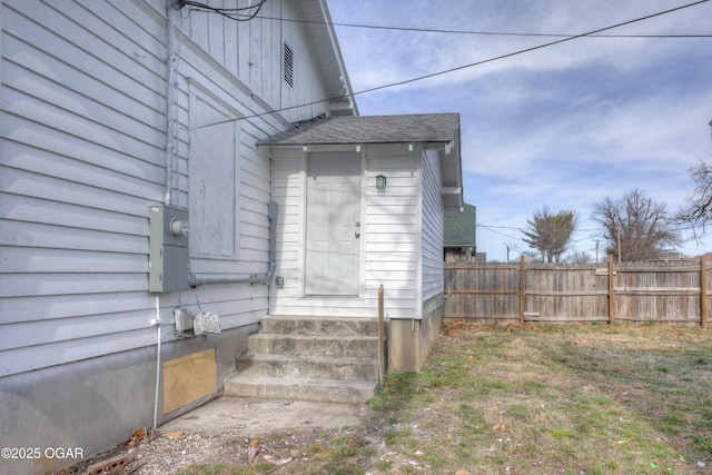 entrance to property with fence and roof with shingles