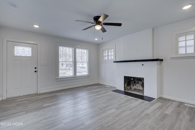 unfurnished living room with visible vents, a fireplace with flush hearth, a ceiling fan, wood finished floors, and baseboards