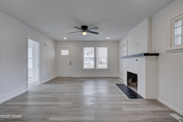 unfurnished living room with visible vents, light wood-style flooring, a fireplace, and ceiling fan