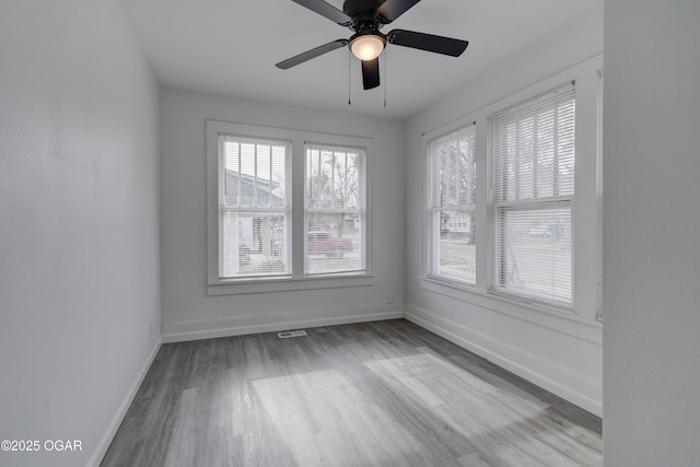 unfurnished room featuring visible vents, a ceiling fan, baseboards, and wood finished floors