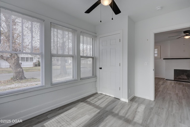 spare room with baseboards, wood finished floors, ceiling fan, and a fireplace