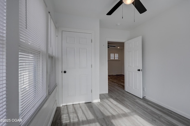 unfurnished bedroom with a ceiling fan, baseboards, and wood finished floors