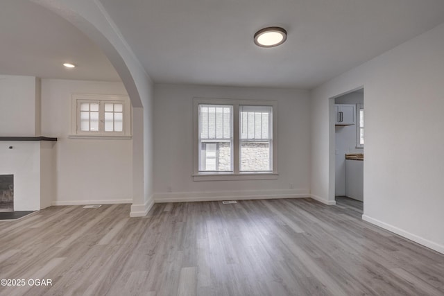 unfurnished living room featuring baseboards, a healthy amount of sunlight, and wood finished floors