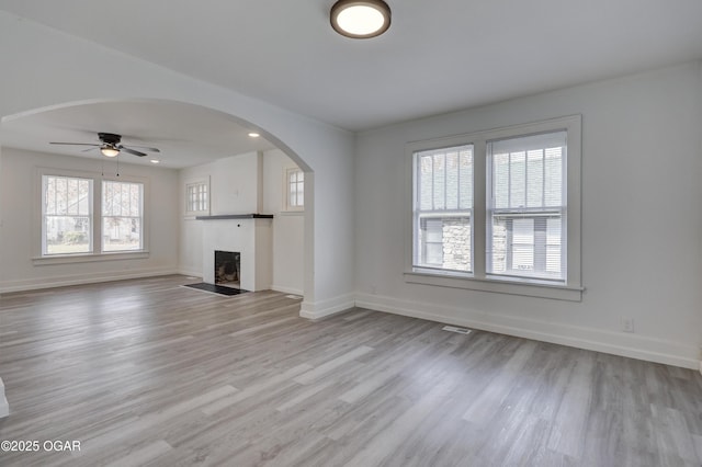 unfurnished living room with plenty of natural light, visible vents, a fireplace with flush hearth, and light wood-type flooring