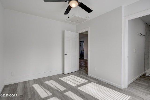 unfurnished bedroom featuring baseboards, attic access, wood finished floors, and a ceiling fan