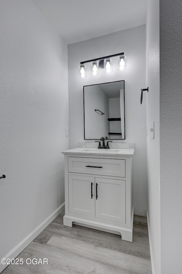 bathroom with vanity, wood finished floors, and baseboards