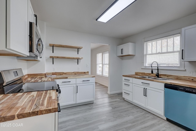 kitchen with a sink, white cabinetry, appliances with stainless steel finishes, butcher block counters, and light wood finished floors