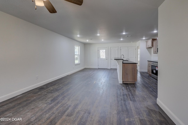 kitchen featuring dark countertops, dark wood-type flooring, baseboards, ceiling fan, and open floor plan