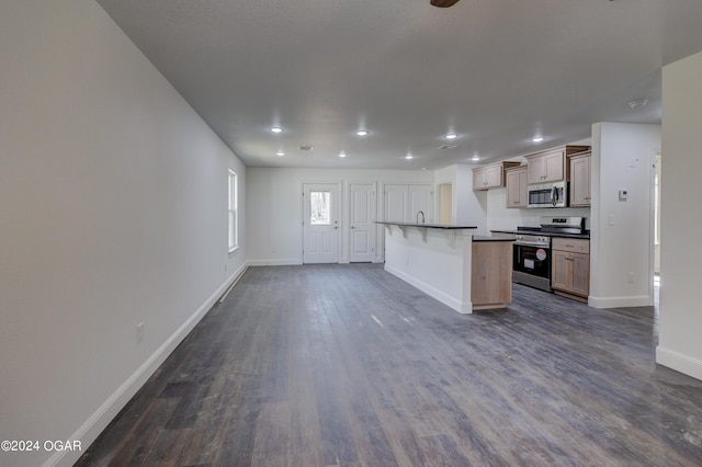 kitchen with baseboards, stainless steel appliances, dark wood-type flooring, dark countertops, and open floor plan