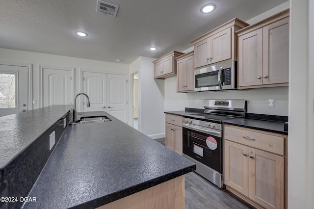 kitchen with dark countertops, recessed lighting, appliances with stainless steel finishes, and a sink