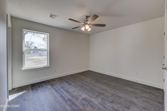 empty room with dark wood finished floors, baseboards, visible vents, and ceiling fan