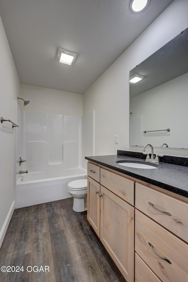 full bathroom with toilet, a textured ceiling, wood finished floors, bathtub / shower combination, and vanity