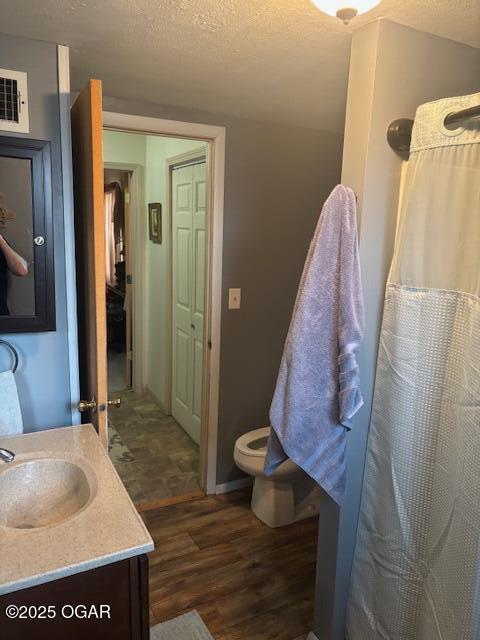 bathroom with vanity, wood finished floors, visible vents, and a textured ceiling