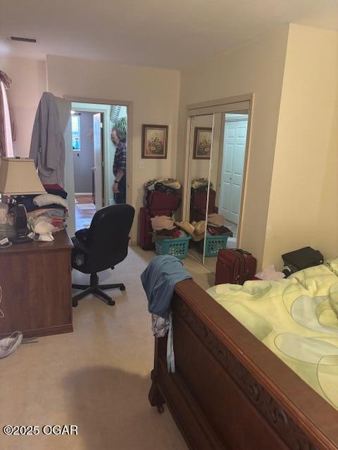 bedroom featuring visible vents, light carpet, and a closet