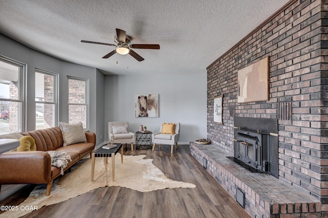 living area featuring a ceiling fan, wood finished floors, baseboards, and a textured ceiling