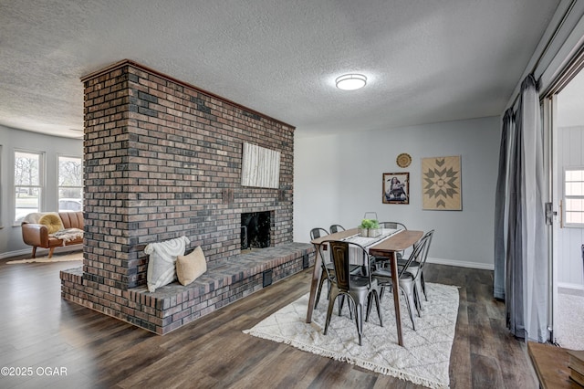 dining area with a wealth of natural light, a textured ceiling, dark wood finished floors, and a fireplace