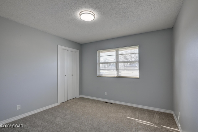 unfurnished bedroom with visible vents, baseboards, carpet floors, a closet, and a textured ceiling