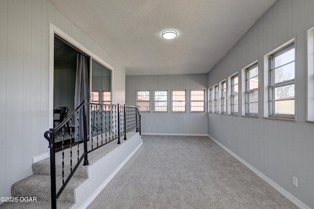 corridor featuring plenty of natural light, baseboards, stairs, and carpet