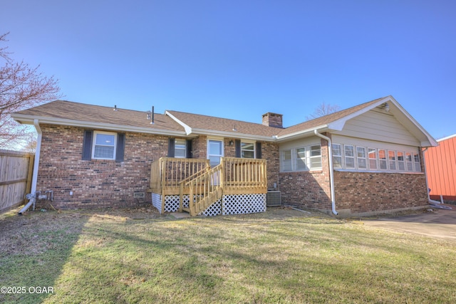 rear view of property featuring a yard, brick siding, a chimney, and fence