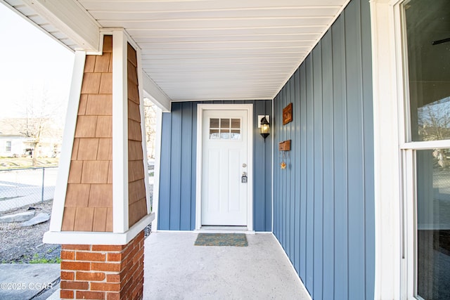 view of exterior entry featuring fence and board and batten siding