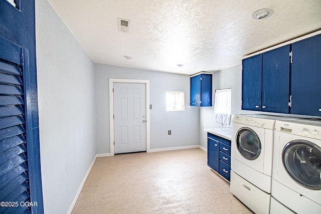 washroom featuring baseboards, a textured wall, cabinet space, a textured ceiling, and washing machine and dryer