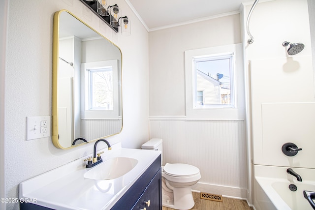 full bathroom with wood finished floors, visible vents, wainscoting, crown molding, and toilet