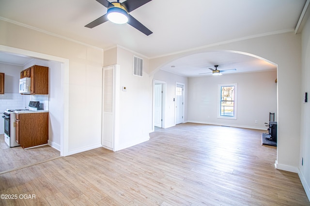 unfurnished living room featuring arched walkways, light wood-style flooring, and ceiling fan