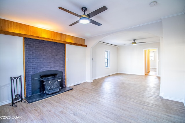 unfurnished living room with arched walkways, wood finished floors, a ceiling fan, and ornamental molding