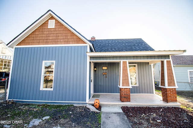 traditional home featuring board and batten siding, covered porch, and a shingled roof