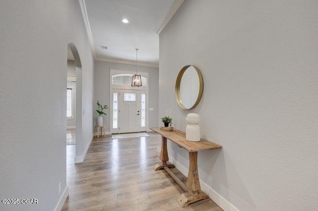 foyer entrance featuring light wood-type flooring, recessed lighting, arched walkways, crown molding, and baseboards