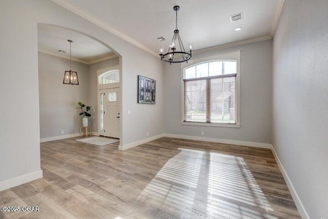 interior space featuring an inviting chandelier, light wood-style floors, arched walkways, and baseboards