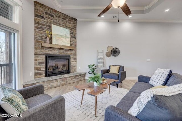 living area featuring ornamental molding, wood finished floors, recessed lighting, a fireplace, and ceiling fan