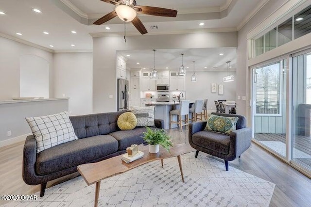 living area featuring recessed lighting, light wood-type flooring, ceiling fan, and ornamental molding