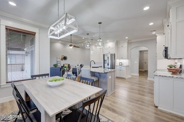 dining room with ornamental molding, a ceiling fan, recessed lighting, arched walkways, and light wood-style floors