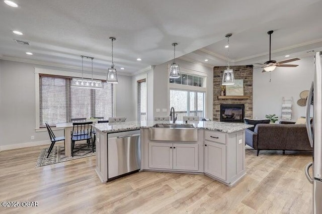 kitchen featuring visible vents, a sink, appliances with stainless steel finishes, a fireplace, and crown molding