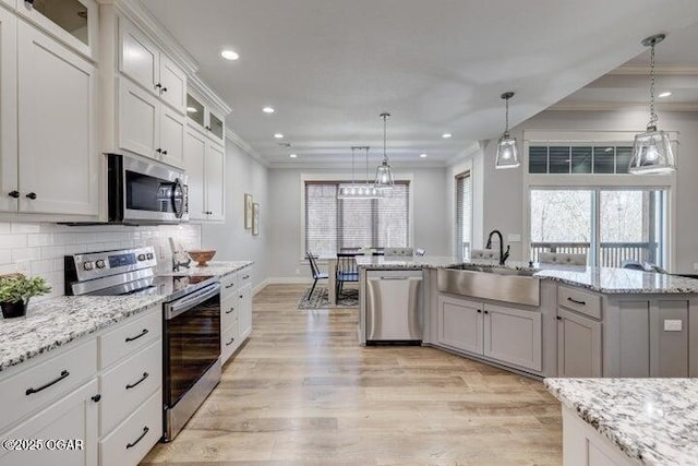 kitchen featuring tasteful backsplash, ornamental molding, light wood-style flooring, stainless steel appliances, and a sink