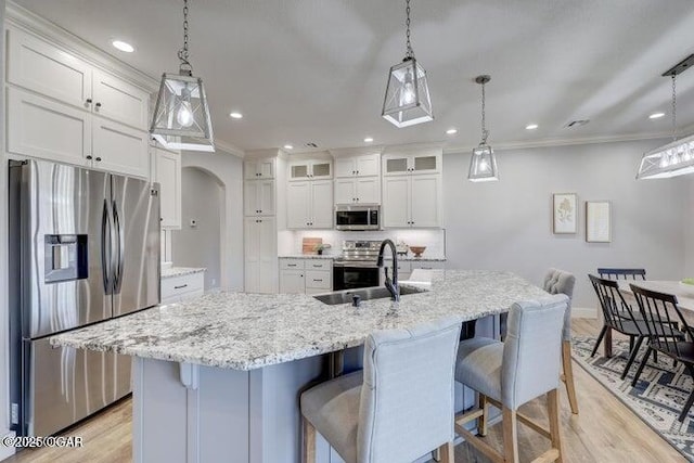 kitchen with a sink, white cabinets, light wood-type flooring, and stainless steel appliances