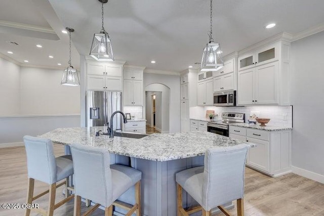 kitchen with a sink, stainless steel appliances, a breakfast bar, and white cabinets