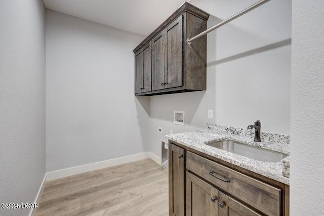 laundry area with a sink, cabinet space, light wood finished floors, hookup for an electric dryer, and hookup for a washing machine