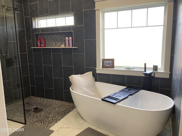 full bathroom featuring a freestanding tub, plenty of natural light, marble finish floor, and a tile shower