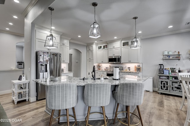 kitchen with white cabinetry, ornamental molding, decorative backsplash, arched walkways, and appliances with stainless steel finishes