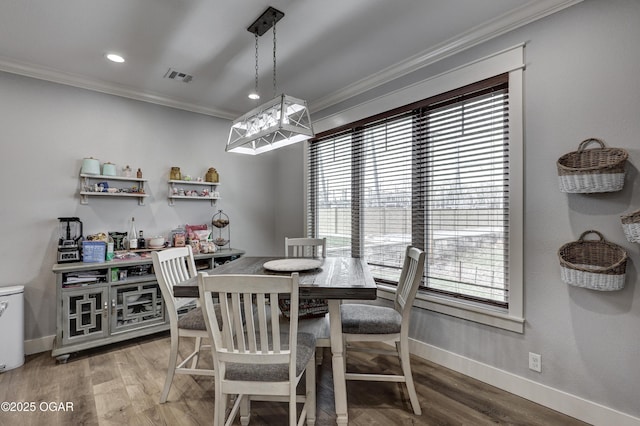 dining room featuring baseboards, light wood-style flooring, visible vents, and crown molding