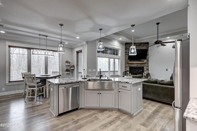 kitchen featuring open floor plan, ornamental molding, a sink, ceiling fan, and appliances with stainless steel finishes