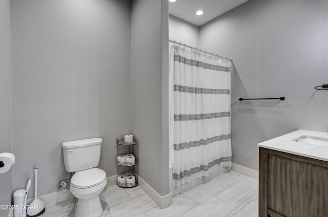 bathroom with toilet, vanity, and baseboards