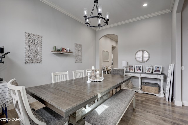 dining space with a chandelier, baseboards, ornamental molding, wood finished floors, and arched walkways