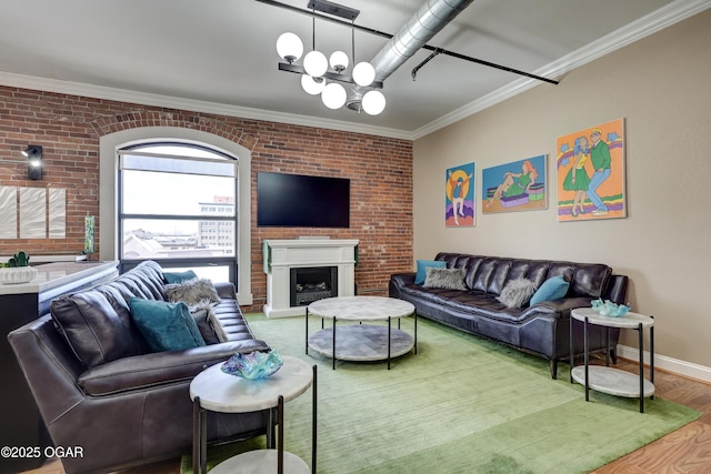 living room featuring an inviting chandelier, crown molding, wood finished floors, and brick wall