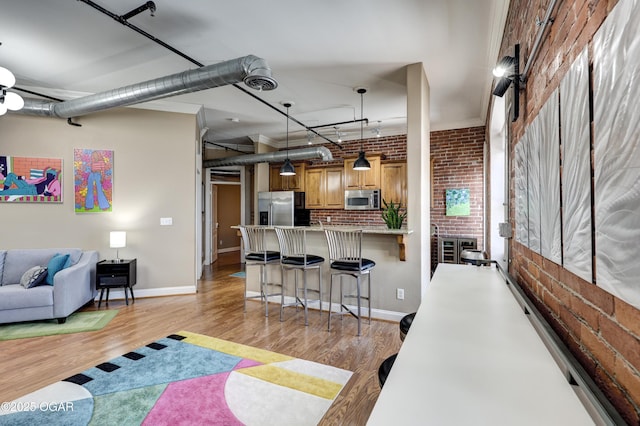 interior space featuring light wood-type flooring, baseboards, and brick wall