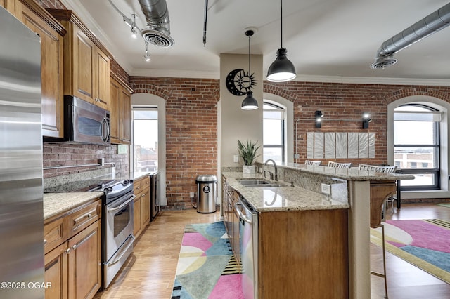 kitchen with a sink, stainless steel appliances, a breakfast bar area, and brick wall