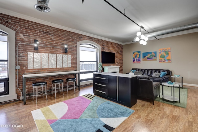 interior space with visible vents, brick wall, crown molding, baseboards, and wood finished floors