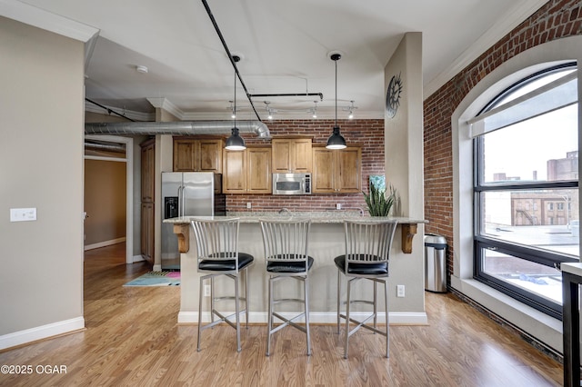 kitchen with a healthy amount of sunlight, appliances with stainless steel finishes, and a kitchen bar